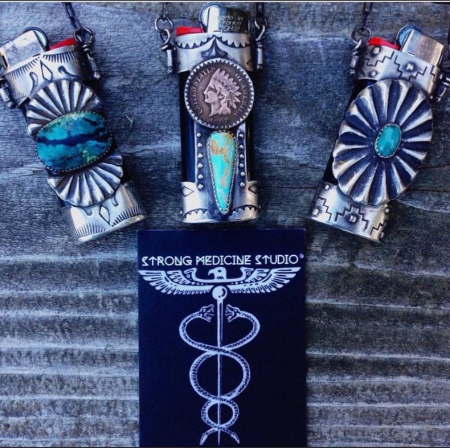Three sterling turquoise FireKeeper lighter cases around the black Strong Medicine Studio card with its winged caduceus mark
